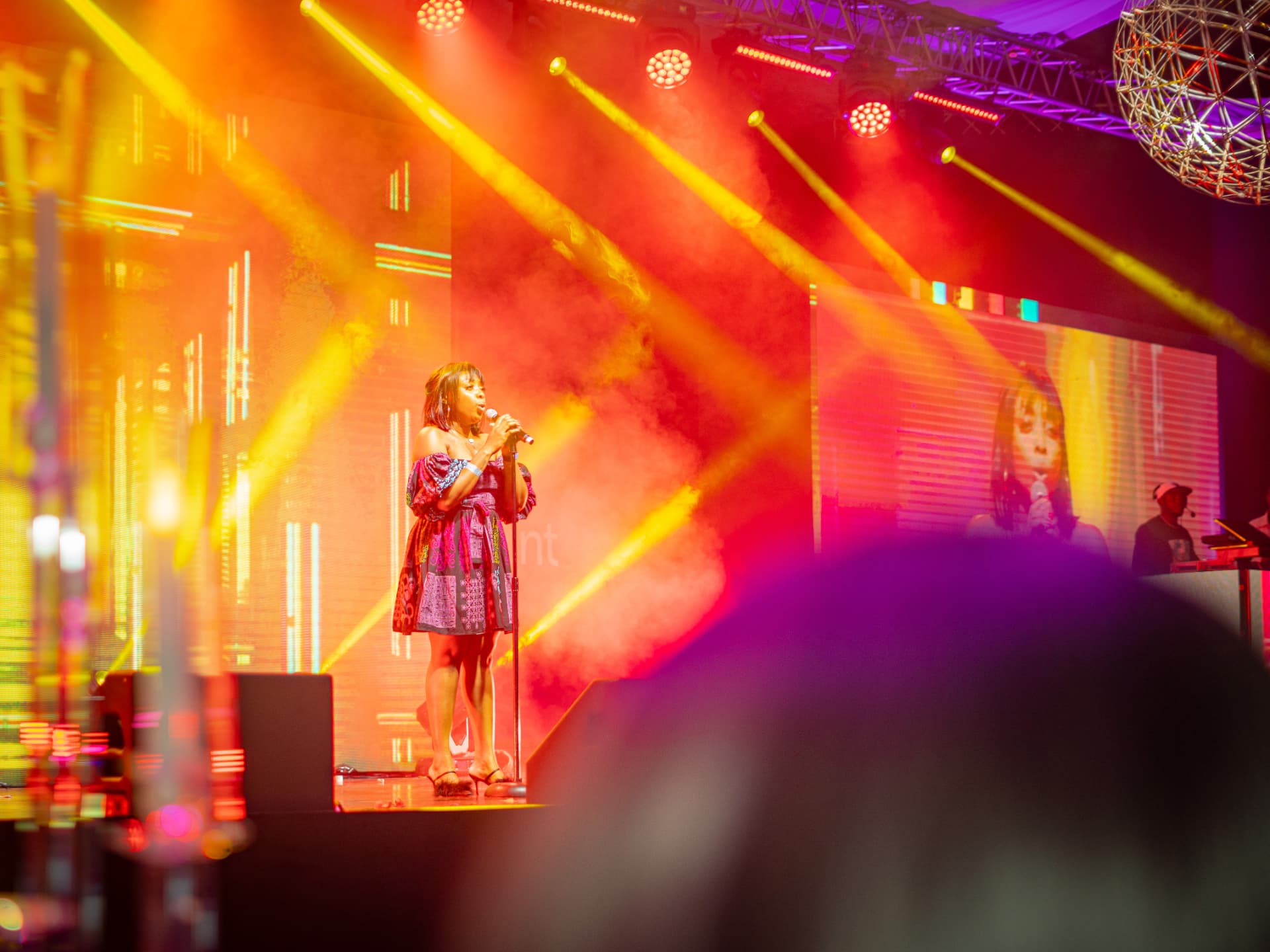 A performer framed by lighting, sound and visual production